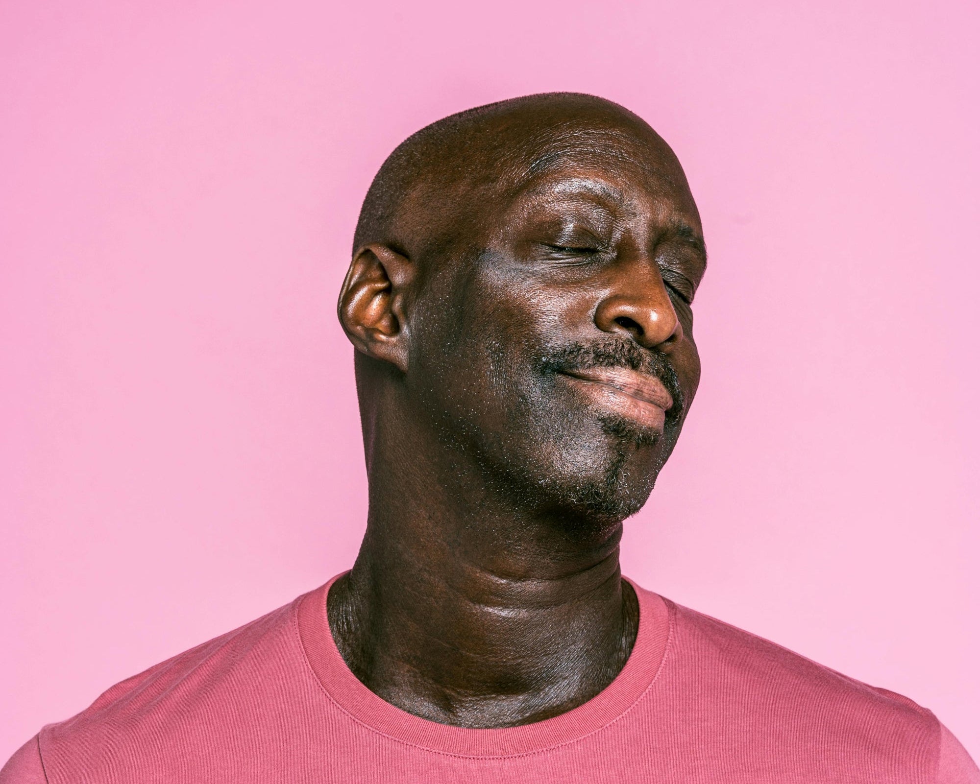 Man wearing a pink shirt against a pink background